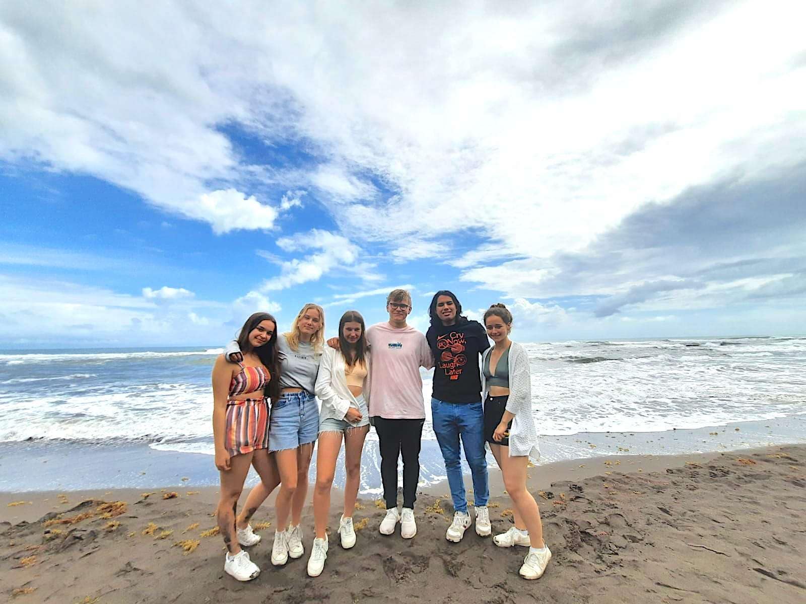 Into uitwisselingsstudent in Brazilië maakt nieuwe vrienden Groep jonge gelukkige mensen arm in arm voor oceaan