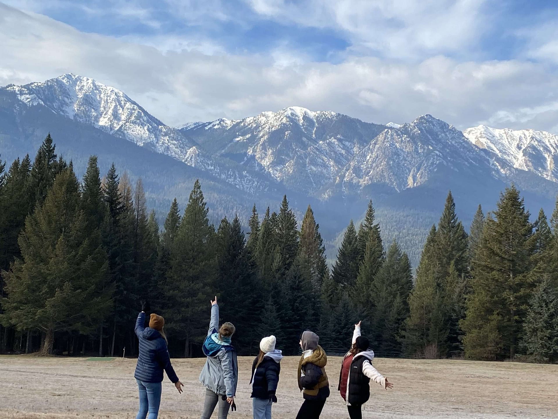 Julia with friends in the mountains Voor tieners vanaf de achterkant wijzend naar een reeks hoge bergen op de achtergrond