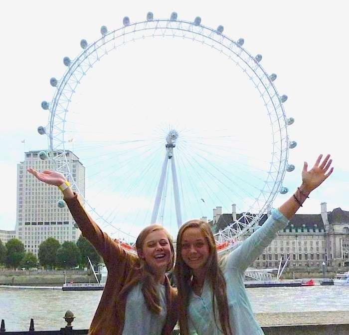 Bente en vriend voor Londen Eye Twee tienermeisjes staan bij de rivier de Theems met het Londen eye op de achtergrond